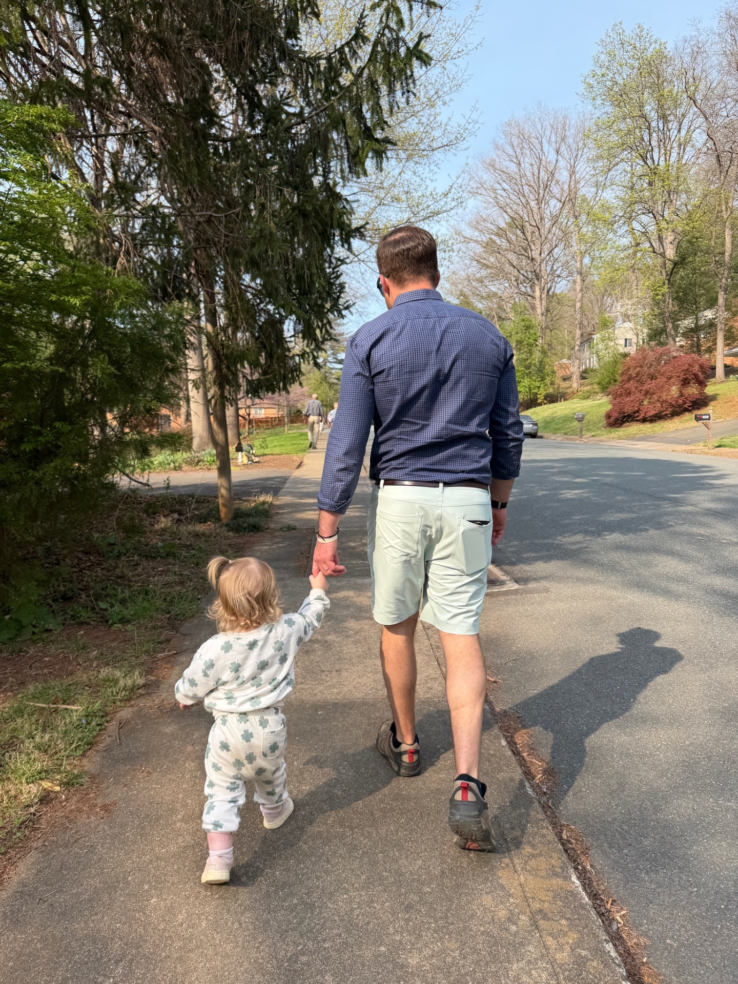 Mark walking hand-in-hand with his young daughter down a tree-lined sidewalk.